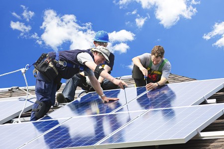 solar panel repair technicians working on solar panels on a roof